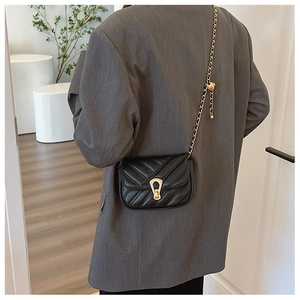 Détail du sac bandoulière matelassé noir avec fermoir fer à cheval doré porté par un mannequin