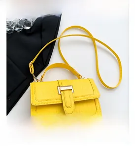Detail view of yellow crocodile embossed leather crossbody bag with gold hardware