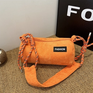 Orange corduroy cylinder crossbody bag with woven rope strap and fashion label