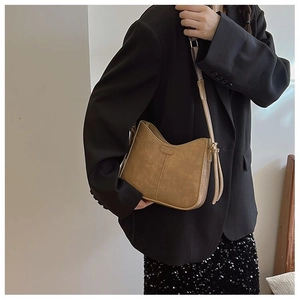 Détail d'un sac besace marron en suédine avec surpiqûres verticales et zip en métal