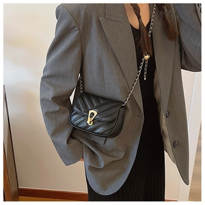 Détail d'un sac à bandoulière en cuir matelassé noir avec fermoir doré et bandoulière chaîne