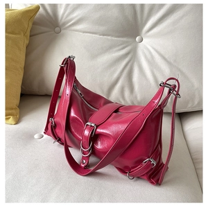 Détail du sac bandoulière en cuir verni rose fuchsia avec boucles argentées et zip