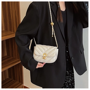Détail de sac à bandoulière matelassé blanc avec chaîne dorée et fermoir serpent