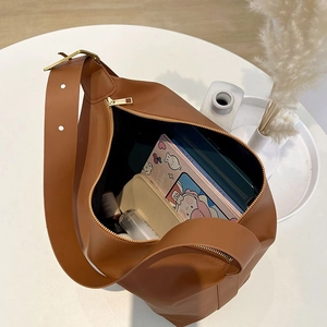 Brown large-capacity PU leather tote bag with wide adjustable strap on a minimalist table