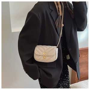 Gros plan sur un sac bandoulière blanc matelassé avec chaîne dorée et fermoir métallique