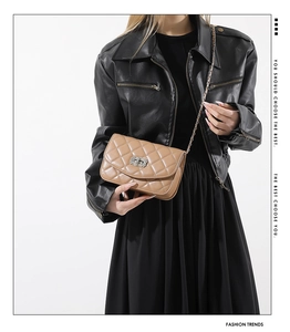 Lifestyle shot of quilted chain crossbody bag in camel brown worn with leather jacket