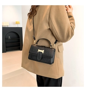 Close-up of black croc-embossed handbag with gold metal H-clasp and leather strap