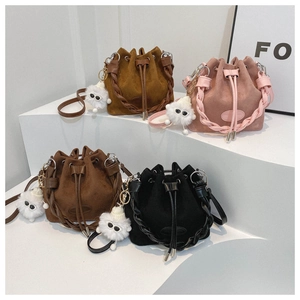 Detail of four matte drawstring bucket bags with braided straps and plush charms