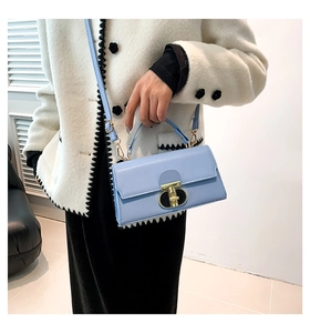 Dettaglio di una borsa a tracolla rettangolare azzurra con elegante chiusura dorata