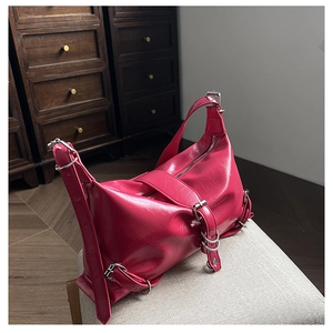 Détail du sac à bandoulière en cuir froissé rose foncé avec boucles argentées et texture