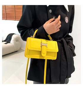 Detail of yellow crocodile texture leather bag with elegant golden H-shaped buckle
