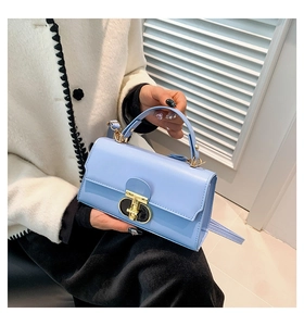 Detail of light blue glossy leather handbag with elegant gold circular metal buckle