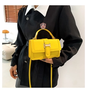 Close-up of bright yellow croc-effect crossbody bag with metallic buckle and handle