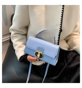 Detail of light blue leather square handbag with golden twist lock and hand-held strap