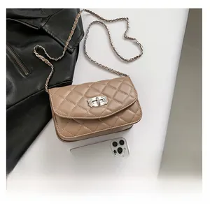 Close-up of beige quilted crossbody bag with metal twist lock and gold chain strap detail