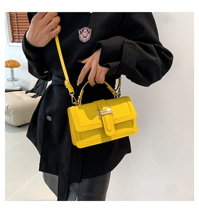 Close-up of yellow crocodile texture leather bag with golden H-shaped clasp and shoulder strap