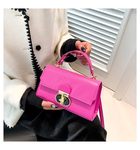 Detail of pink crossbody bag featuring a golden T-shaped twist lock and top handle