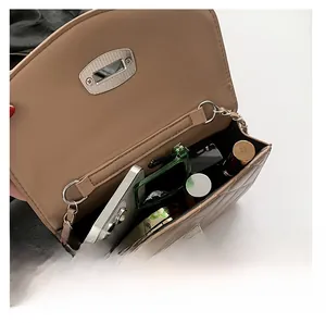 Detail view of khaki quilted chain bag interior holding phone and cosmetics