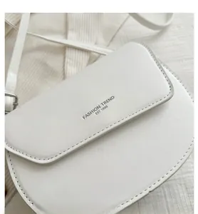 Détail du sac selle en cuir blanc montrant le texte embossé Fashion Trend Est 1996