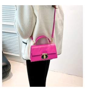 Dettaglio della borsa squadrata rosa acceso con chiusura dorata su cappotto bianco