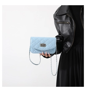 Detail of light blue quilted crossbody bag featuring silver twist lock and chain strap
