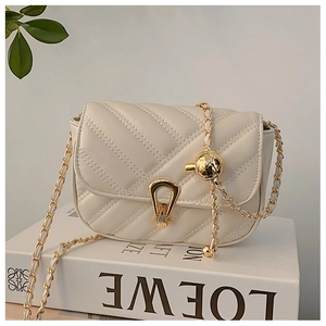 Macro detail of beige quilted leather texture and gold horseshoe buckle on crossbody bag
