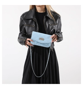 Detail of light blue quilted crossbody bag with silver chain strap on black outfit