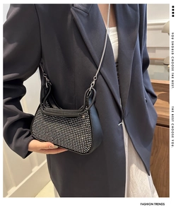 Detail of a black half-moon shoulder bag with shimmering rhinestones and silver chain strap