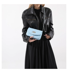 Close-up of light blue quilted chain bag with silver twist lock on model in black outfit