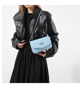 Detail of light blue quilted chain strap bag with silver twist lock on leather jacket