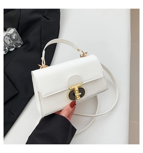 Close-up of white leather square bag featuring a T-shaped gold buckle and top handle