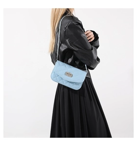 Close-up of light blue quilted crossbody bag with metal chain and turn-lock closure
