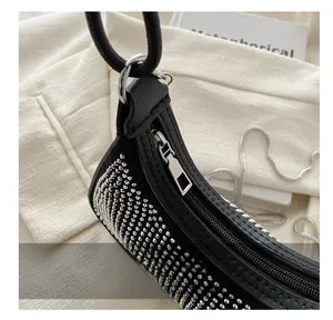 Close-up of smooth metal zipper and sparkling rhinestones on black crescent shoulder bag