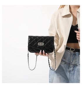 Detailed view of black quilted crossbody bag with silver turn-lock and chain strap