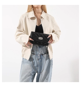 Detail of classic black quilted crossbody bag with silver chain strap and metal lock