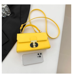 Detail of yellow rectangular crossbody bag showing the golden T-shaped twist lock and top handle