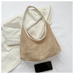 Detail view of woven hobo bag with cream leather straps on a white suit jacket