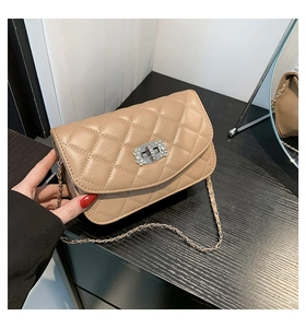 Close-up of quilted beige chain bag featuring a rhinestone-embellished metal turn-lock