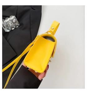 Detail view of the yellow crossbody bag side structure with gold studs and PU leather