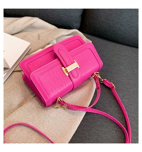 Detailed view of magenta crocodile pattern leather handbag with gold H-shaped clasp