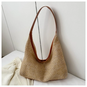 Close-up of woven straw tote bag featuring brown leather straps and natural texture