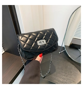 Detail of black quilted chain bag with silver jewel-encrusted twist lock and metal strap