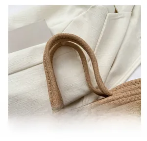 Detail der handgewebten Strohtasche mit robusten braunen Griffen und Spitzen-Schleife