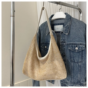 Detail of handwoven straw tote bag with elegant white leather handles and stitching