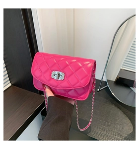 Detail of fuchsia quilted crossbody bag with silver diamond twist lock and chain strap