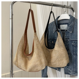 Detail of straw woven hobo bags with brown and black leather straps in a casual style