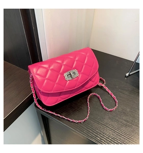 Detail of fuchsia quilted crossbody bag with rhinestone buckle and silver chain strap
