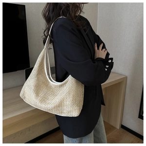 Detailed side view of a large woven hobo shoulder bag with white leather trim and straps