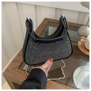 Détail du sac hobo noir avec strass et chaîne argentée porté à la main