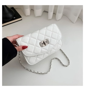Macro detail of white quilted crossbody bag with rhinestone buckle and silver chain